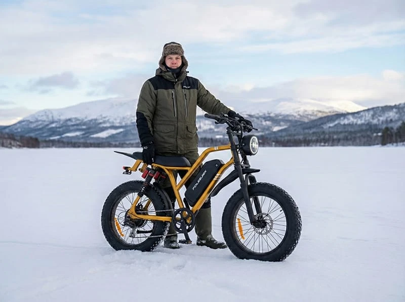 A winter cyclist wearing warm gloves and gear riding the Poleejiek F6, equipped with fenders to protect against snow spray.